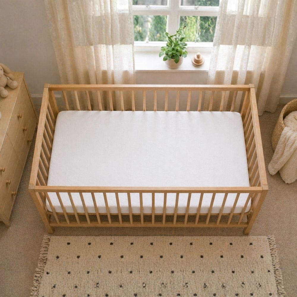 Firm baby cot mattress fitted securely inside a wooden cot.