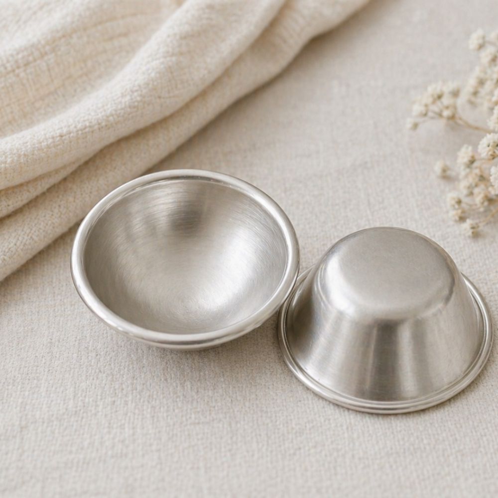 Reusable silver nipple cups to help protect sore nipples during breastfeeding.