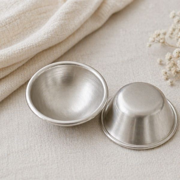 Reusable silver nipple cups to help protect sore nipples during breastfeeding.